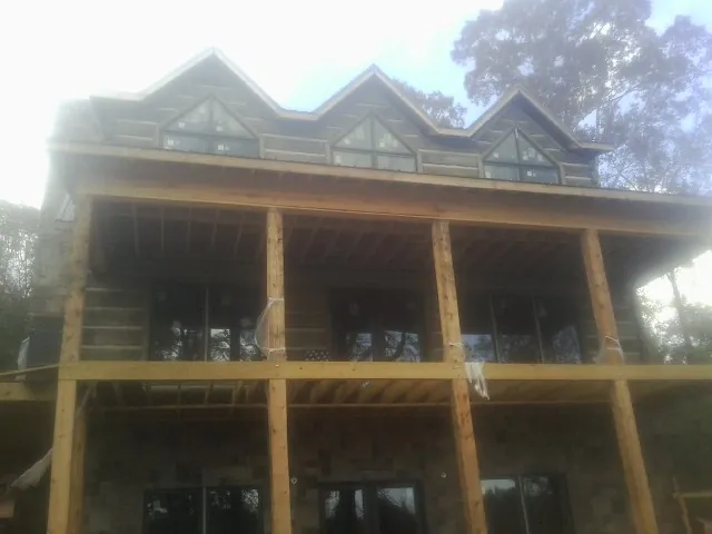 Dormers and porch framing on a large log home under construction — Roof Coating work by our crew in Gloucester Point