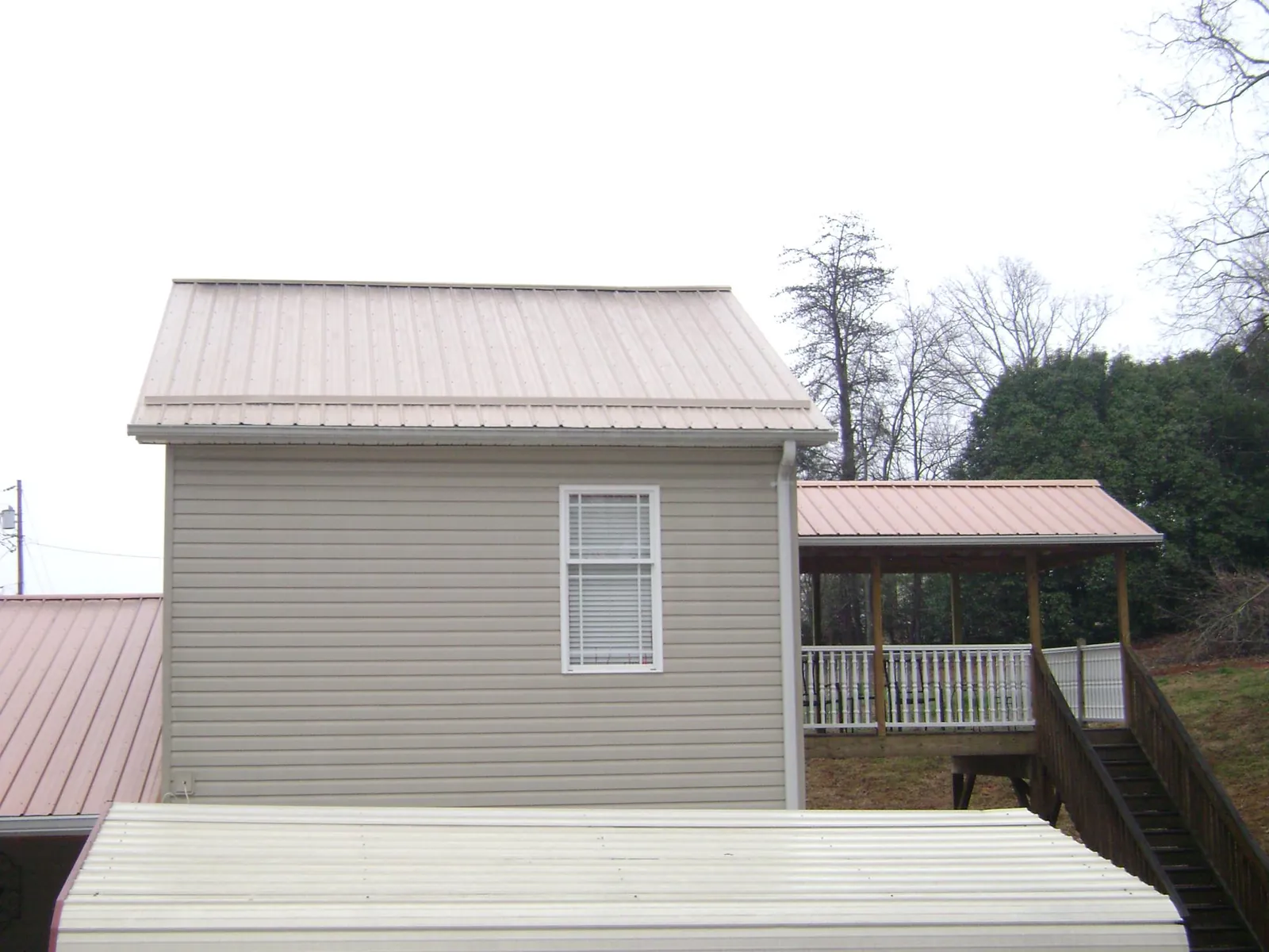 Tan metal roofs on a two story addition and attached porch, from a Roof Replacement job in Gloucester Point