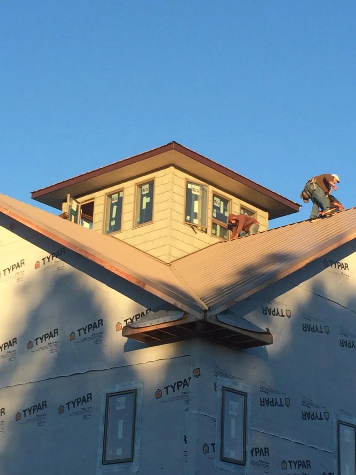 Roofers working around a rooftop cupola on a new metal roof at sunset — Roof Waterproofing in Gloucester Point by Roofing Brothers